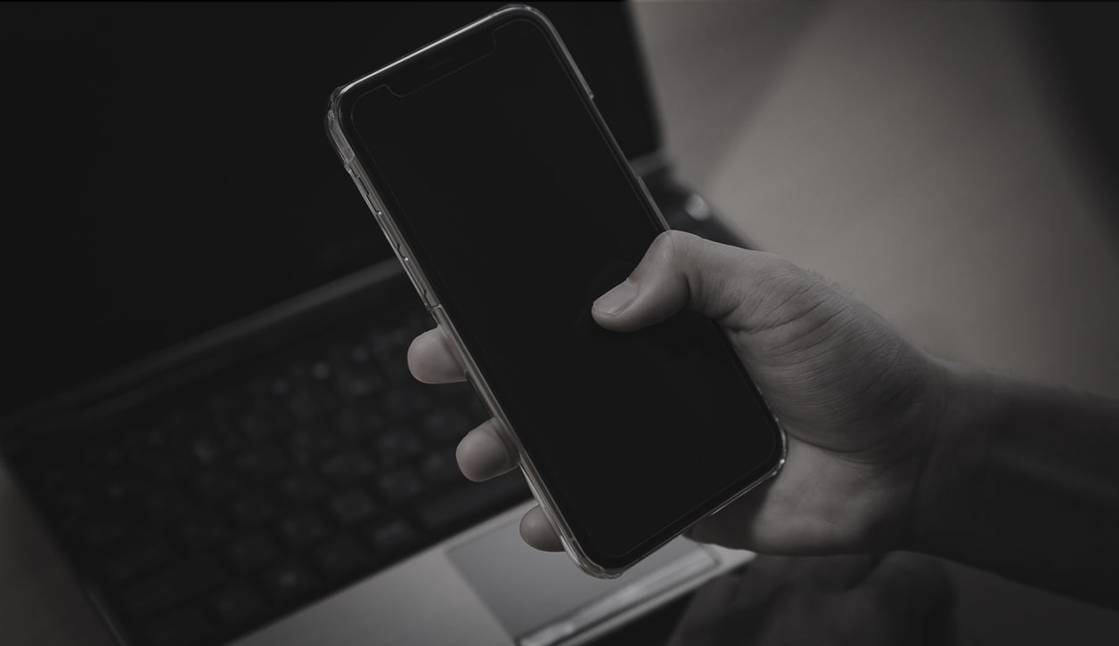 ノートパソコンの前でスマホを操作する人